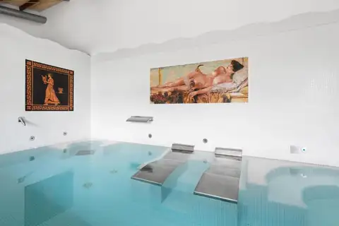 Piscina interior del spa con camas de hidromasaje y mosaicos de inspiración clásica en el Áurea Palacio de Sober