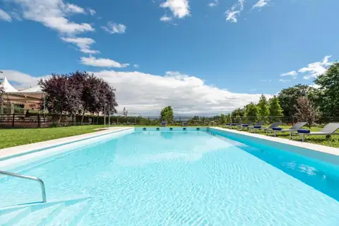 Piscina exterior al aire libre rodeada de jardín y hamacas en el Áurea Palacio de Sober