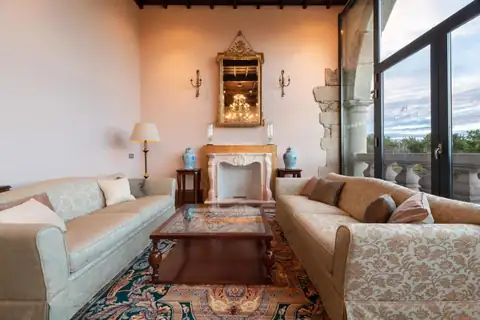 Salón con chimenea de mármol y sofás junto a un gran ventanal en el Áurea Palacio de Sober
