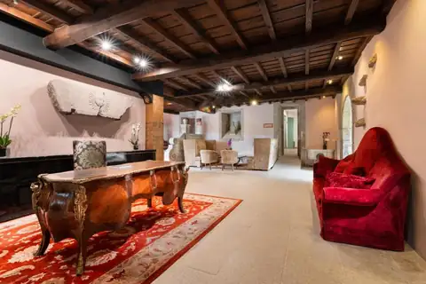 Recepción con escritorio antiguo, techo de madera y sofá rojo en el Áurea Palacio de Sober
