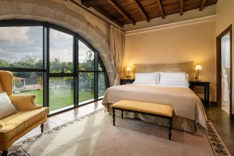 Habitación doble con gran ventanal en arco sobre los jardines del Áurea Palacio de Sober