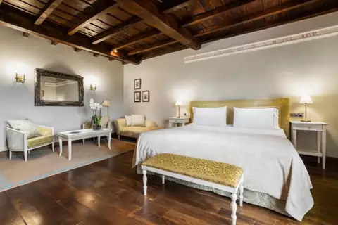Habitación con techo de vigas de madera, cama doble y zona de estar en el Áurea Palacio de Sober