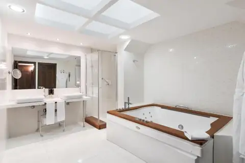 Baño de suite con bañera de hidromasaje y doble lavabo en el Áurea Palacio de Sober