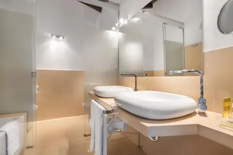 Baño con doble lavabo de diseño y ducha acristalada en una habitación del Áurea Palacio de Sober
