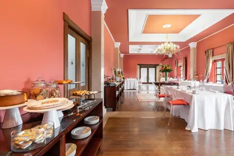 Comedor del desayuno con mesas vestidas y paredes rojas en el Áurea Palacio de Sober
