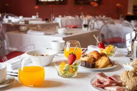 Desayuno servido en mesa con zumo de naranja, fruta y bollería en el Áurea Palacio de Sober