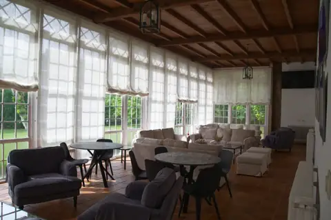 Salón con techo de madera, sofás y mesas junto a grandes ventanales en el Gran Balneario do Carballiño