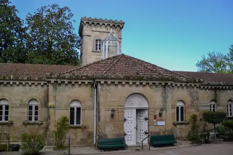 Edificio histórico de piedra con torre y puerta en arco del Gran Balneario do Carballiño
