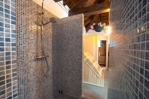 Ducha de mosaico junto a la sauna de madera en el spa de As Torres da Hermida