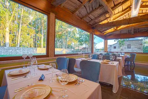 Comedor acristalado con mesas vestidas y vistas al bosque en As Torres da Hermida