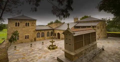 Patio empedrado con hórreo y fuente ante las torres del Hotel Boutique As Torres da Hermida