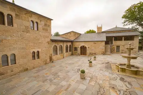 Patio interior con fuente de piedra y fachadas de sillería en As Torres da Hermida