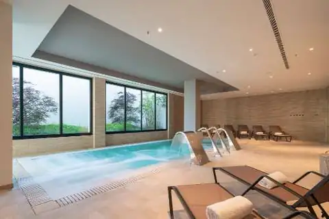 Piscina de hidroterapia con ventanales al jardín y tumbonas en el Hotel Attica21 Vigo