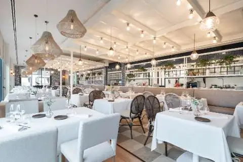 Restaurante con mesas vestidas de blanco y lámparas de fibra en el Hotel Attica21 Vigo