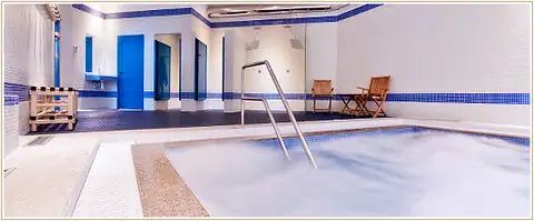 Vista lateral de la piscina de chorros con cenefa azul en el spa del Hotel Auditorio Santiago