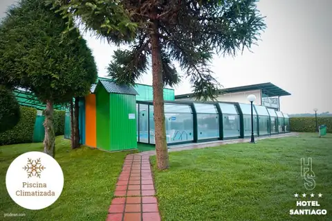 Jardín con césped, árboles y piscina cubierta acristalada del Hotel Auditorio Santiago en Lugo