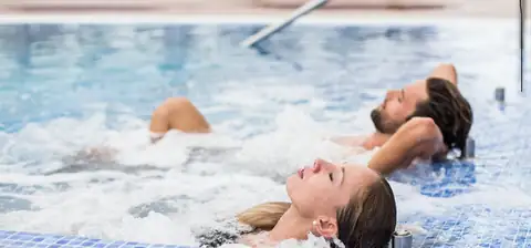 Pareja relajándose entre burbujas en la piscina de hidromasaje del Hotel Nuevo Astur & Spa