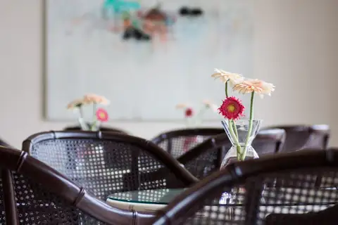 Detalle de mesas con sillas de mimbre y jarrones de gerberas en el Hotel Nuevo Astur & Spa