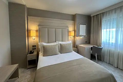 Habitación doble con cabecero tapizado, escritorio y ventanal en el Hotel Nuevo Astur & Spa