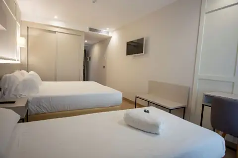 Habitación con dos camas, televisión y armario empotrado en el Playa de Foz Hotel & Spa