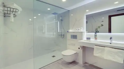 Baño moderno de mármol con ducha de obra y mampara en el Playa de Foz Hotel & Spa