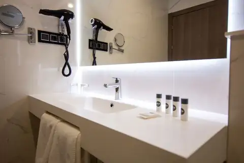 Lavabo con espejo retroiluminado, secador y amenities en el Playa de Foz Hotel & Spa