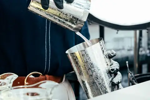 Camarero sirviendo una bebida con coctelera de plata en el bar del Hotel Plaza A Coruña