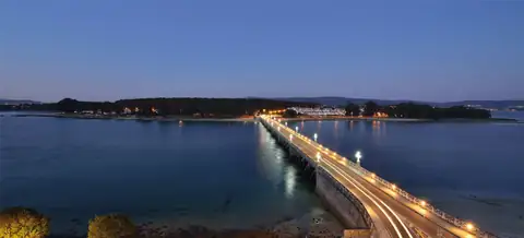 Puente iluminado de La Toja al anochecer sobre la ría, junto al Hotel Puente de La Toja