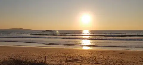 Puesta de sol sobre una playa de arena cercana al Hotel Puente de La Toja en O Grove