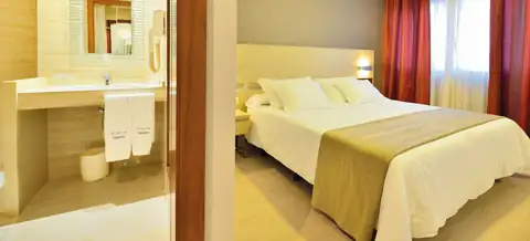 Habitación con cama de matrimonio y baño con lavabo en el Hotel Puente de La Toja