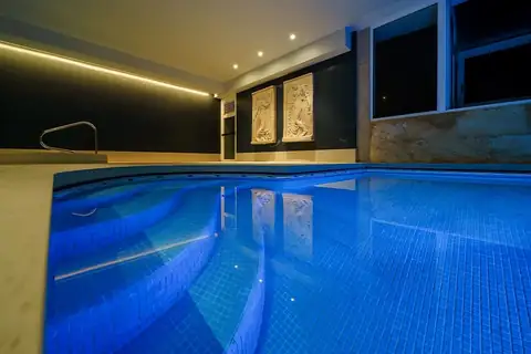 Piscina interior con iluminación azul y escalera de acceso en el spa del Hotel Atlántico