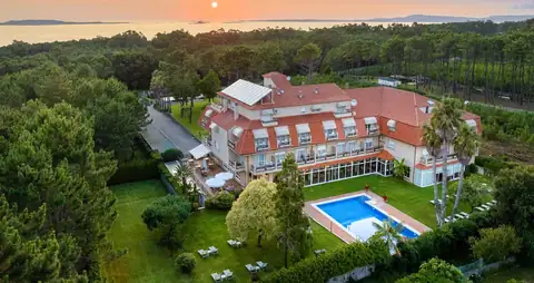 Vista aérea del Hotel Spa Atlántico entre pinares con la piscina y el mar al atardecer