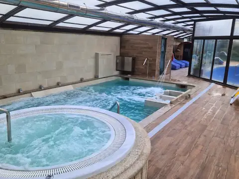 Jacuzzi circular en primer plano y piscina con camas de agua del Hotel Spa Bosque Mar