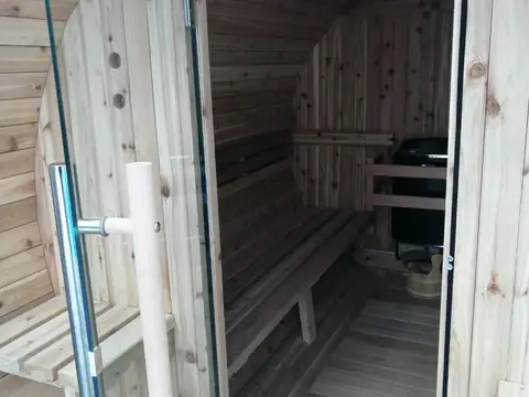 Interior de la sauna de madera con bancos y estufa en el Hotel Spa Bosque Mar