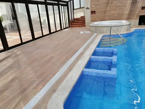 Piscina azul con escalones de mosaico y jacuzzi al fondo en el spa del Hotel Spa Bosque Mar