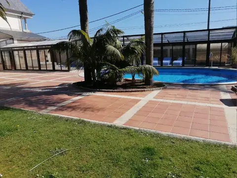 Piscina exterior con palmeras y césped junto al pabellón acristalado del Hotel Spa Bosque Mar