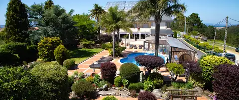 Vista elevada de los jardines con palmeras y la piscina exterior del Hotel Spa Bosque Mar