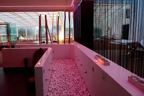 Pasillo de cantos rodados con luz rosada en el circuito del spa del Hotel Congreso & Spa