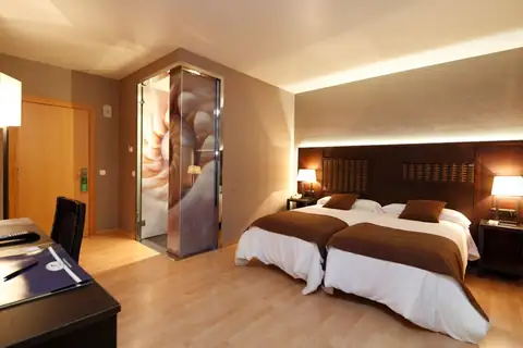 Habitación con dos camas y baño con mampara decorada en el Hotel Congreso & Spa