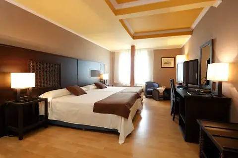 Amplia habitación con dos camas, escritorio y televisión en el Hotel Congreso & Spa