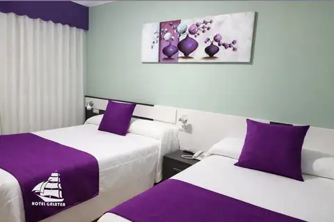 Habitación con dos camas y detalles en morado en el Hotel Spa Galatea de Burela