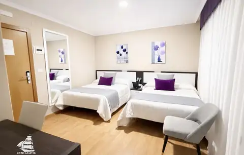 Habitación luminosa con dos camas, sillón y espejo en el Hotel Spa Galatea de Burela