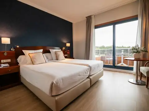 Habitación con dos camas y ventanal con vistas al exterior en el Hotel Spa Galatea de Sanxenxo