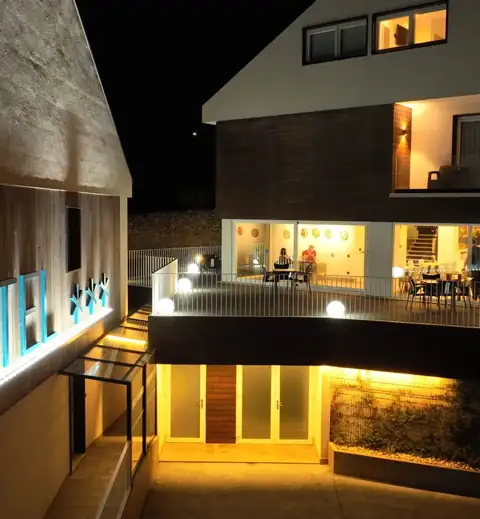 Fachada iluminada de noche con terraza y comedor acristalado del Hotel Spa Meiga do Mar