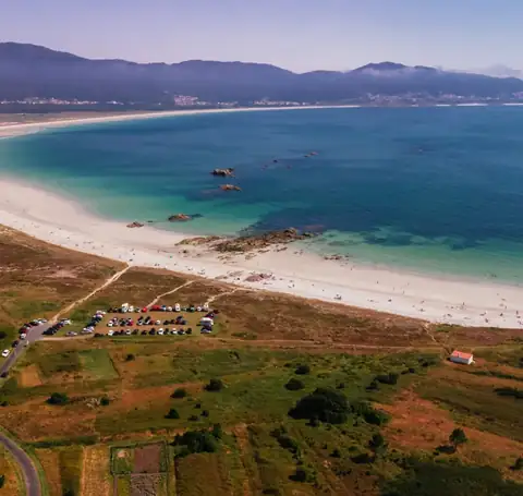 Vista aérea de una amplia playa de arena blanca y aguas turquesa cerca del Hotel Spa Meiga do Mar