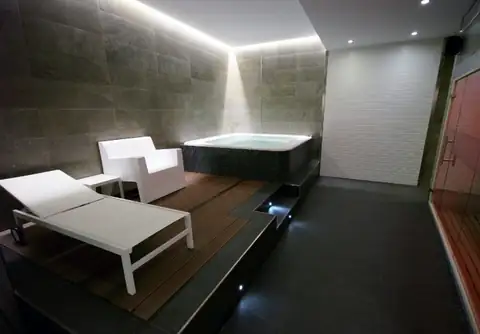 Zona de relax con tumbona, butaca y jacuzzi en el spa del Hotel Spa Nanín Playa