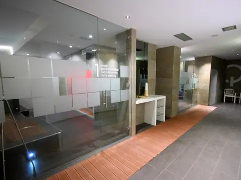 Pasillo del spa con cabinas acristaladas y suelo de madera en el Hotel Spa Nanín Playa