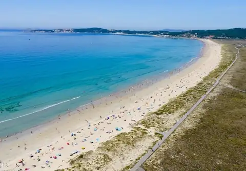 Vista aérea de una larga playa de arena y dunas cerca del Hotel Spa Nanín Playa