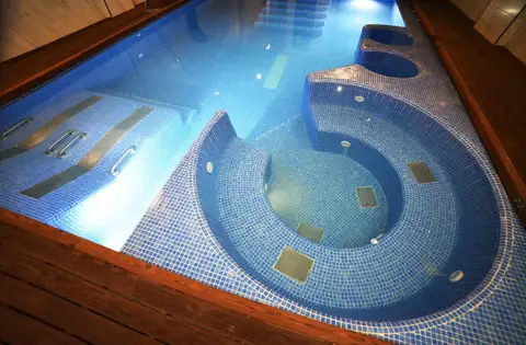 Vista cenital de la piscina de mosaico azul con jacuzzi semicircular en el IMI Hotel & Spa
