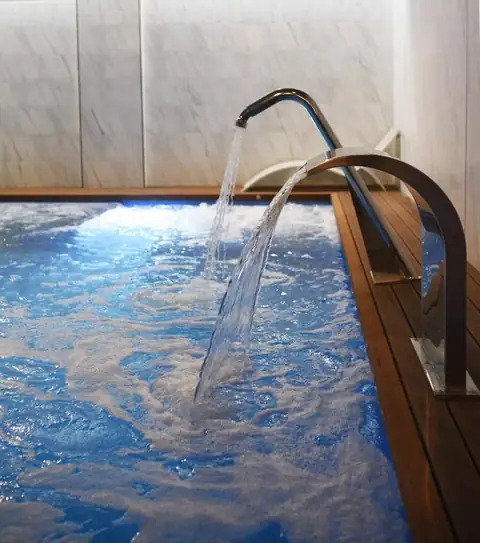 Cascada de agua sobre el vaso de hidromasaje con luz azul en el spa del IMI Hotel & Spa